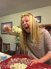 student with blonde hair taking a comically large bite of russian salad from red bowl