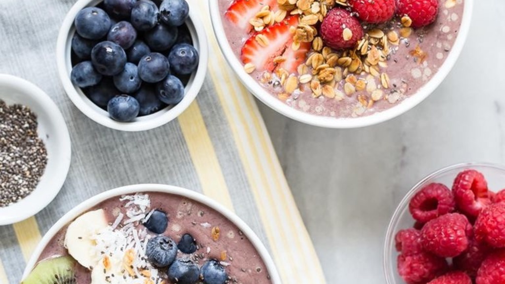 two acai bowls with fruits surrounding them